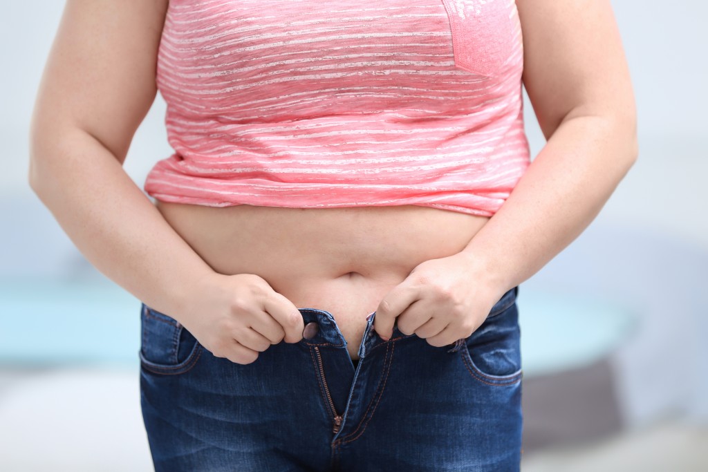 Woman trying to put on her tight jeans