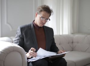 man sitting down holding papers reading