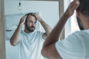 man touching his hair in front of mirror